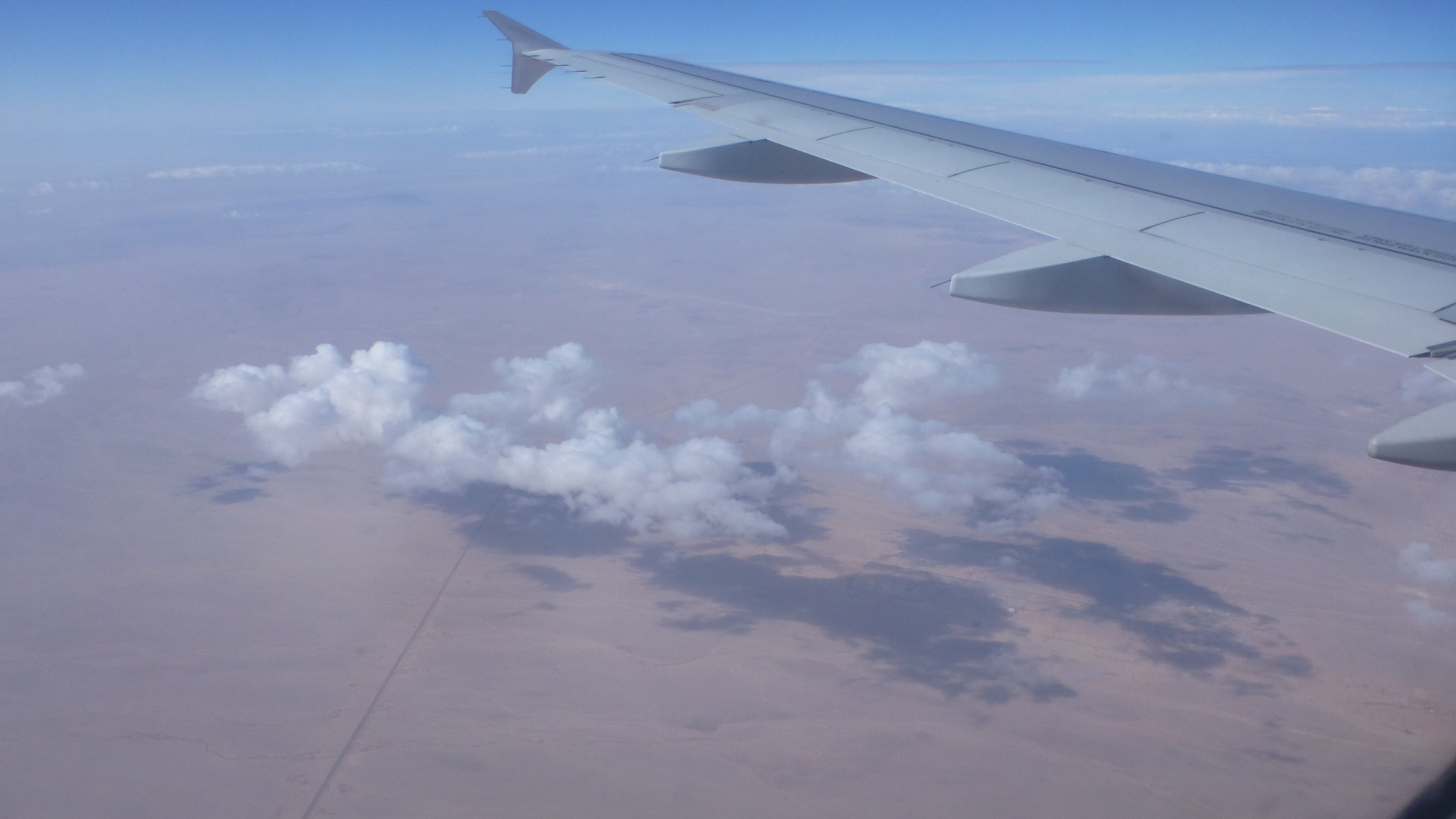 On our flight to Cairo, I can see clouds and their shadows over the desert.