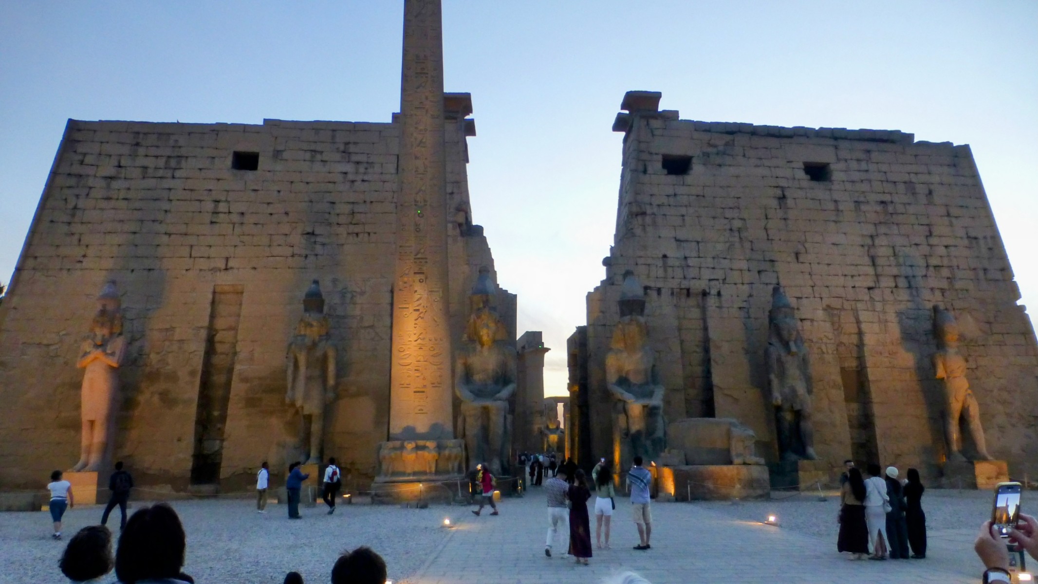 The entrance to Luxor Temple is flanked by six colossal statues of Pharaoh Ramses II, carved from granite. There are two large seated statues and four standing statues. In front of the gateway there was also a pair of obelisks, but only one remains. The other now in Paris acquired in trade by King Louis for the clock at the Mohammed Ali Mosque.