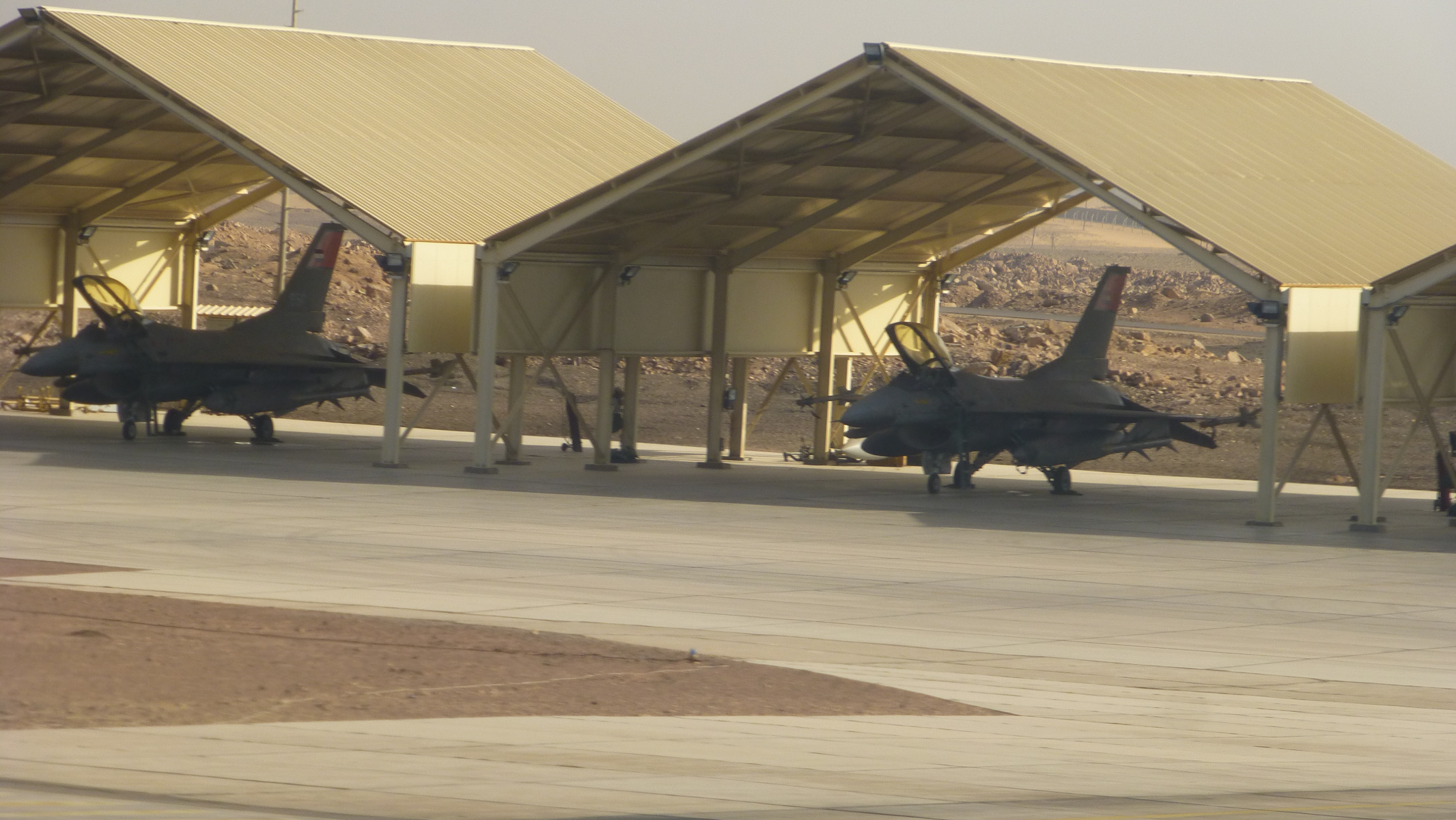 As the plane accelerated on the runway, I caught this picture of what appear to be F16s lined up with the cockpits open and ready for takeoff. (Open cockpits don't seem too smart with all of the blowing sand!)