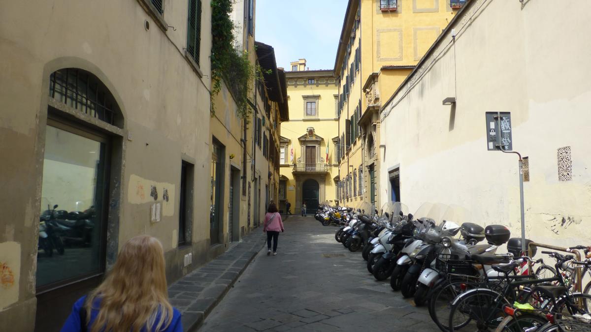 A narrow street in Florence lined with bicycles and scooters