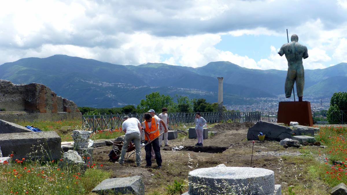 An archeological dig in progress. In the background is the sculpture "Daedalus" by the Polish artist Igor Mitoraj. The sculpture was first exhibited in May of 2016 and remains as a permanent gift to the Italian people.